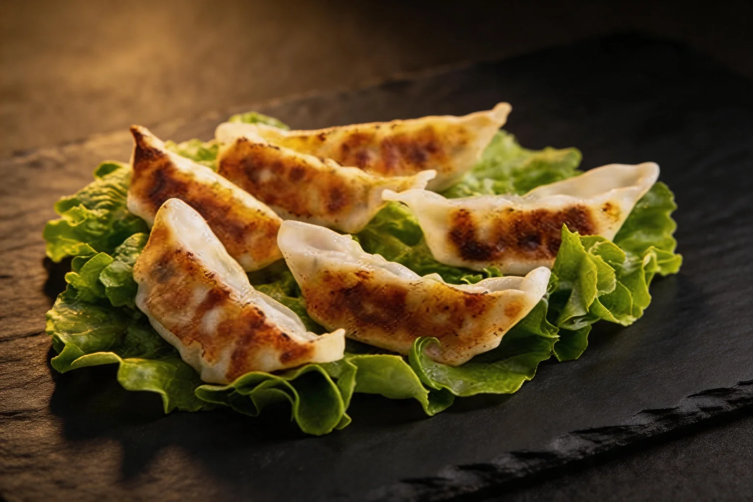 Six gyozas dorés sur un lit de salade, fond de pierre sombre