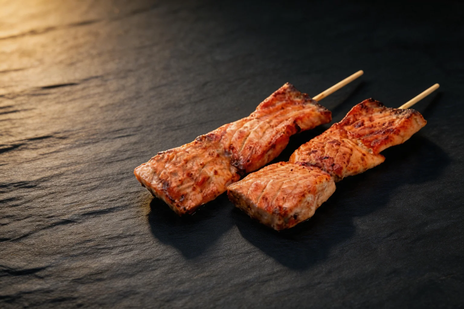 Deux brochettes de saumon grillées, fond de pierre sombre